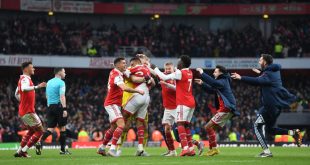 Arsenal players and staff celebrate on the pitch after Reiss Nelson scored their team