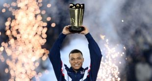 Kylian Mbappe holds a trophy aloft in a ceremony after PSG