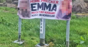 Banner calling out "home wrecker" with her face and work place on display is plastered by a roadside