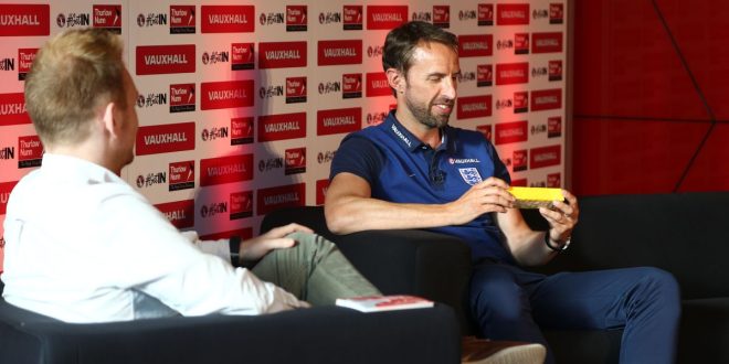 Gareth Southgate holds a yellow packet of custard cream biscuits given to him in a Vauxhall car dealership in Milton Keynes by young fans. Match of the Day writer / presenter Matthew Ketchell looks on