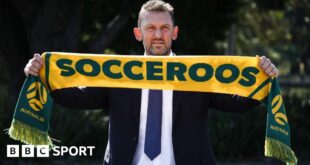 Tony Popovic holding an Australia scarf above his head