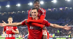 Chris Wood celebrates with his arms outstretched and Anthony Elanga jumping on his shoulders.