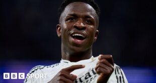 Vinicius Jr points to the Real Madrid badge