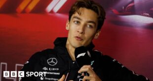 Mercedes driver George Russell speaking into a microphone with the F1 logo during the drivers' press conference for the Las Vegas Grand Prix