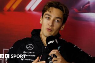 Mercedes driver George Russell speaking into a microphone with the F1 logo during the drivers' press conference for the Las Vegas Grand Prix