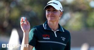 English golfer Charley Hull holds up the ball after making a putt during the third round of The Annika