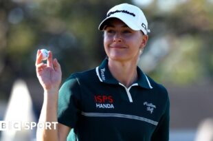 English golfer Charley Hull holds up the ball after making a putt during the third round of The Annika