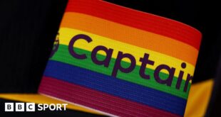 A rainbow-coloured Premier League captain's armband sits in front of a black background