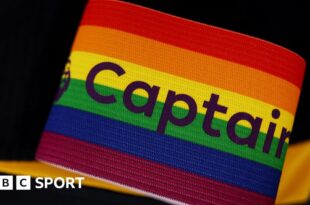 A rainbow-coloured Premier League captain's armband sits in front of a black background